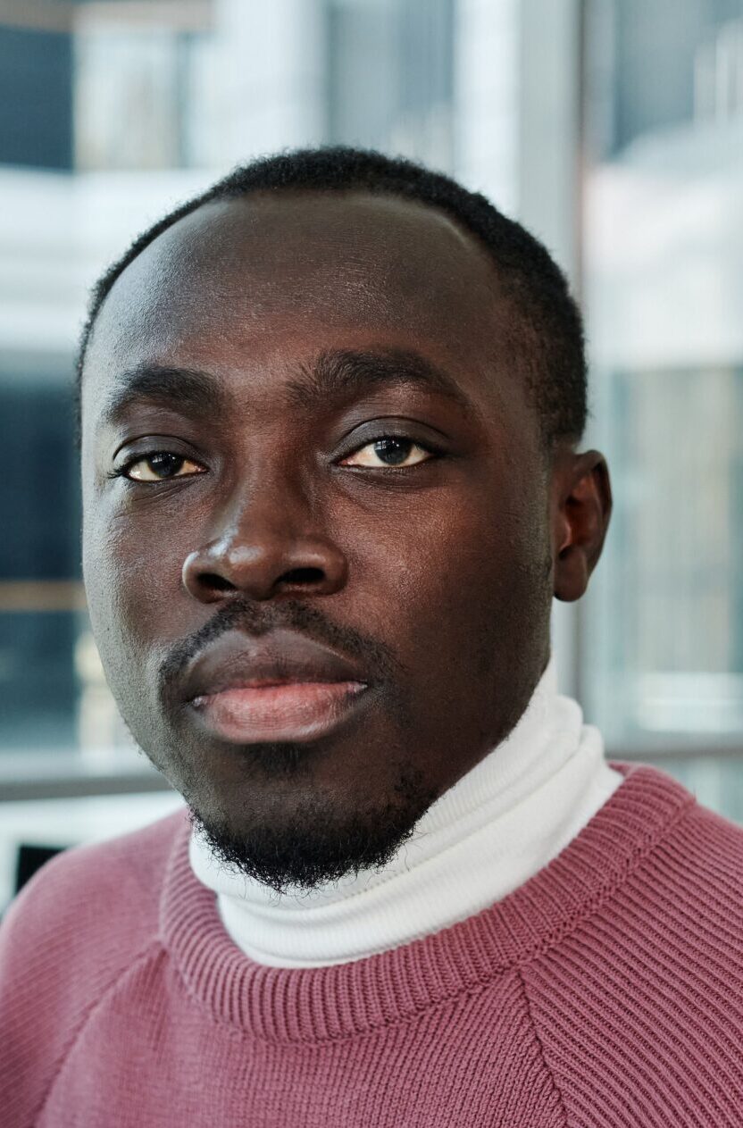 Portrait of a confident man in a cozy sweater in a bright, modern office environment.